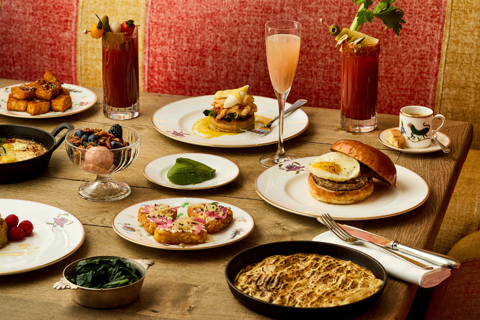 A wide shot of brunch dishes being served at Oscar: there are various brunch-style mains, sides and cocktails on the tables
