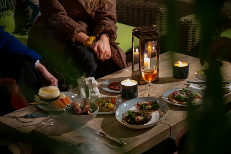 A selection of dishes and cocktails on a table on Ham Yard roof terrace
