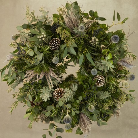 A wreath featuring pinecones and winter florals, made by The Real Flower Company