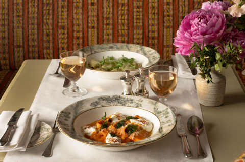 A close-up wide angle shot of a table set up for dinner at Warren Street Bar. There are dishes of vodka rigatoni and morel ravioli