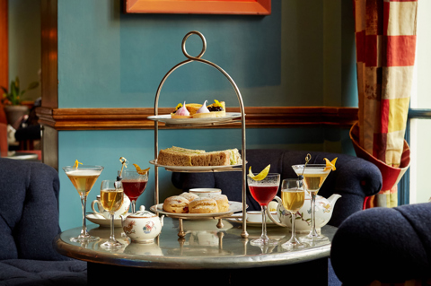 An image of the Afternoon Tea with a Twist at Oscar, Charlotte Street Hotel. The table displays the afternoon tea set up and cocktails.
