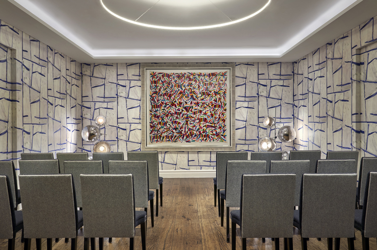 An image of the conference set up, with chairs in rows, in the Sandra Blow private event room, in The Soho Hotel. With 3 rows of 8 chairs across with a break in the middle creating an aisle.