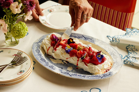 A close-up wide angle shot of the strawberry and lime meringue roulade being served onto a smaller plate
