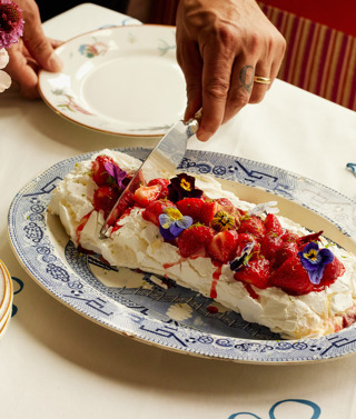 A close-up wide angle shot of the strawberry and lime meringue roulade being served onto a smaller plate