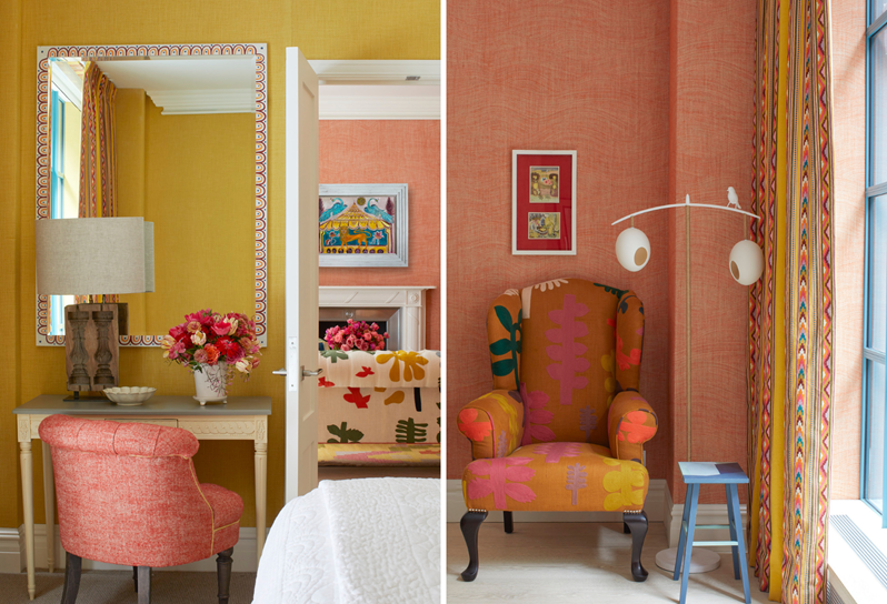 A small wooden desk with an orange tub chair. On the desk there is a vase of flowers and a mirror hangs above it. A multicoloured wing armchair sits against an orange fabric wall. A decorative floor lamp and a wooden stool sit next to the chair