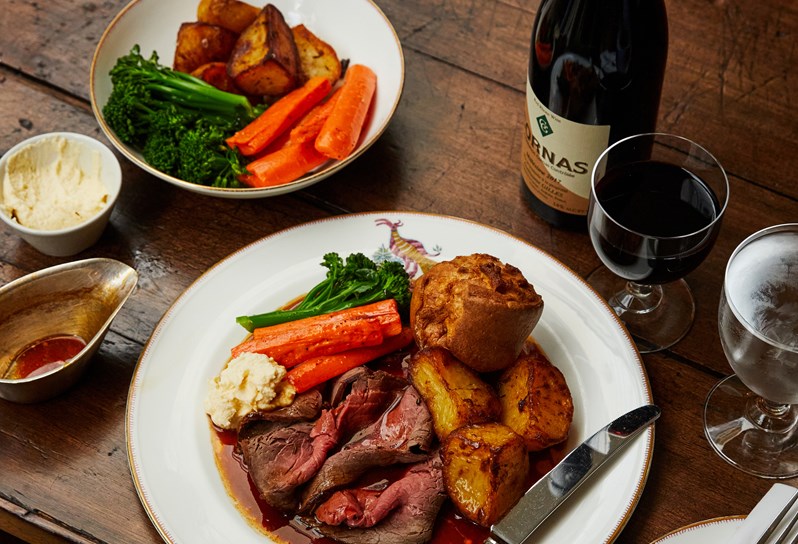 Roast dish and sides with glass of wine on wooden table