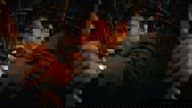 A still showing the main character from the film "How to Make a Killing" pointing a bow and arrow. 