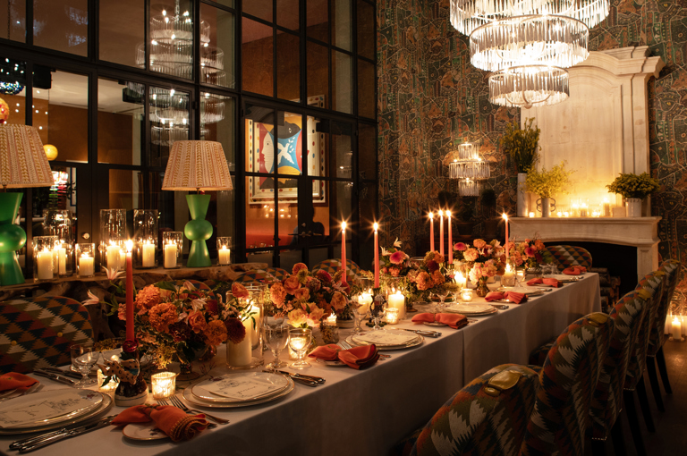 Image of a long table set up for dinner with dim candle lighting in The Orangery at Crosby Street Hotel.  