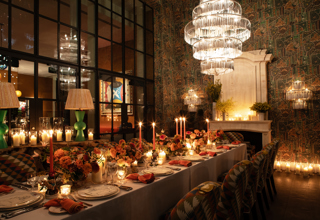 Image of a long table set up for dinner with dim candle lighting in The Orangery at Crosby Street Hotel.  