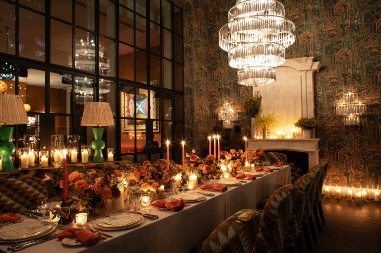 Image of a long table set up for dinner with dim candle lighting in The Orangery at Crosby Street Hotel.