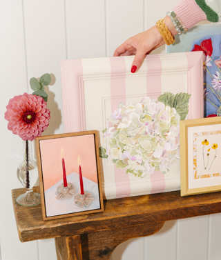 A close up various framed artworks by Domenica Marland on a wooden console table.