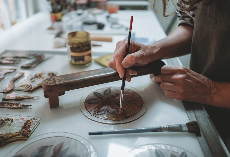 A close up image of Flora Jamieson in her studio designing her stained glass artwork, this image is used to promote her stained glass workshop at Haymarket Hotel.