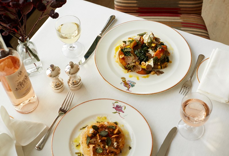 Two seats table set up with different starters on either side and each a glass of either rosé or white wine.