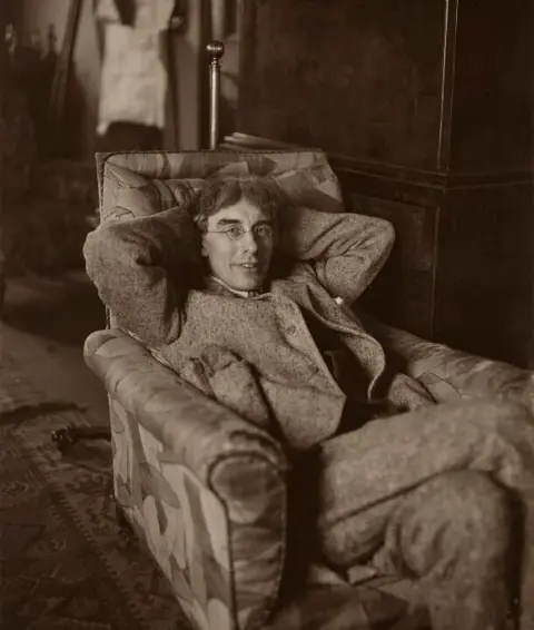 A black and white photography of artist Roger Fry sat in an armchair