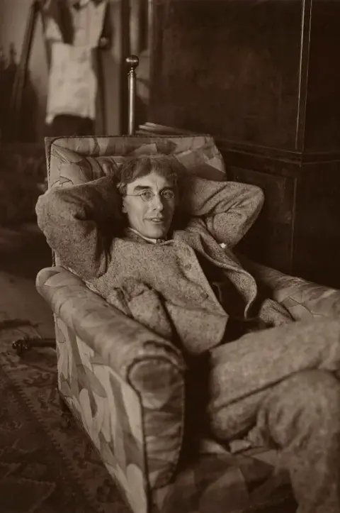 A black and white photography of artist Roger Fry sat in an armchair