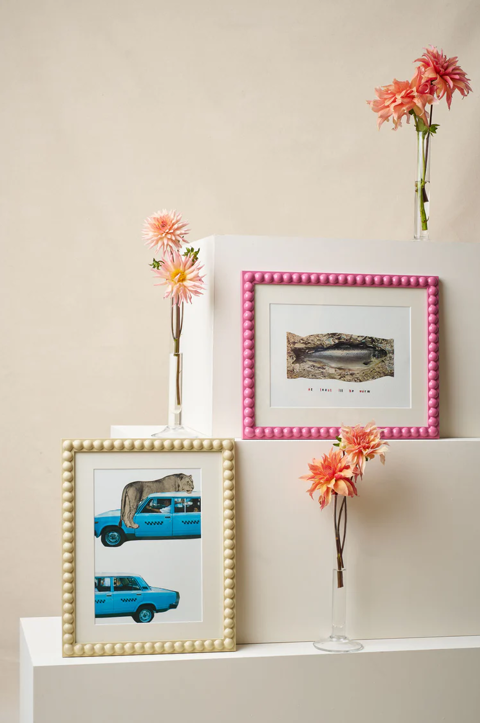 Three large white boxes of descending in size stacked on top of each other. On two edges are bobbin frames by Domenica Marland