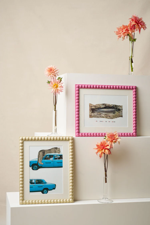 Three large white boxes of descending in size stacked on top of each other. On two edges are bobbin frames by Domenica Marland