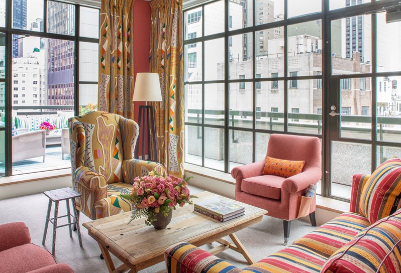 A large, whimsical bright yellow living room with inviting lounge furniture and floor to ceiling Crittall windows