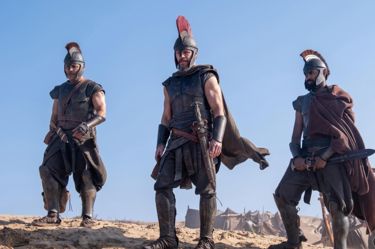 A still from 'The Odyssey'. Three men dressed in ancient Greek armour and tunics for war stand in a desert
