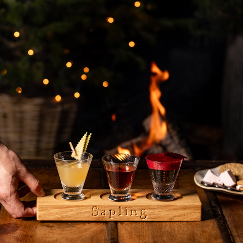 A flight of three cocktails are placed on a table 