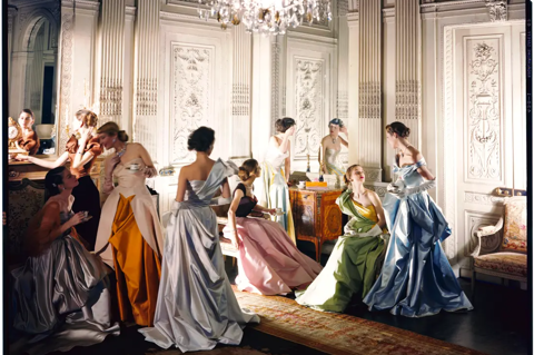 A group of women in coloured evening dresses pose in ballroom 