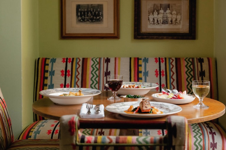 This portrait image shows multiple dishes from The potting Shed, Dorset Squares, A La Carte Menu on Tall Trees Crockery, there is a chicken dish, a cauliflower dish and a salad. 