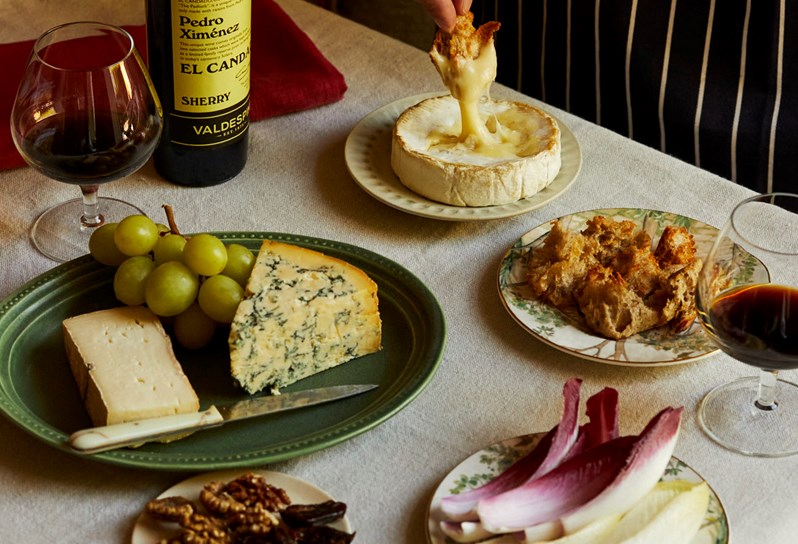 Close up of cheeses on table, with oozing camembert and sherry on the table