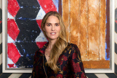 A portrait of Willow Kemp standing against an abstract painting