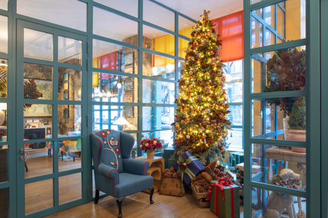 A festive corner with a Christmas tree and presents underneath next to an armchair in the lobby at Warren Street Hotel