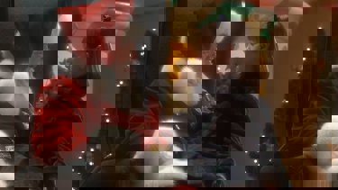 A still from 'Miracle on 34th Street'. A little girl sits on the lap of Santa Claus, they are looking at one another