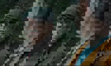 A still from the film "Glenrothan": Two men stand outside facing one another, the focus being an elderly man wearing a flat cap