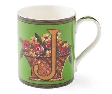 The gold "J" on this emerald green mug sits among a basket overflowing with yellow and red flowers.