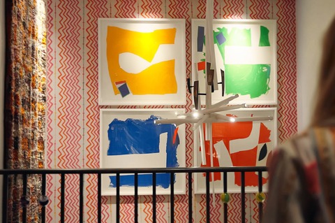 The back of Firmdale Art Ambassador and Design Director Willow Kemp out of focus looking at artwork hanging in the stairwell at Ham Yard Hotel