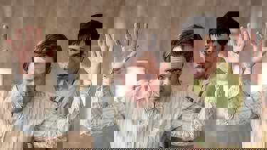 A still from the film "Dead Man's Wire" showing two men, the one in front with his hands in the air.