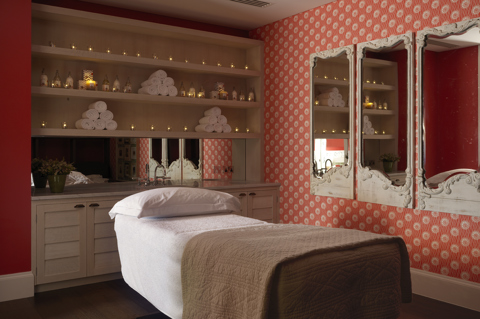 Diagonal shot of a single treatment room, featuring a massage table with fresh white towels, in the Soholistic Spa at Ham Yard Hotel