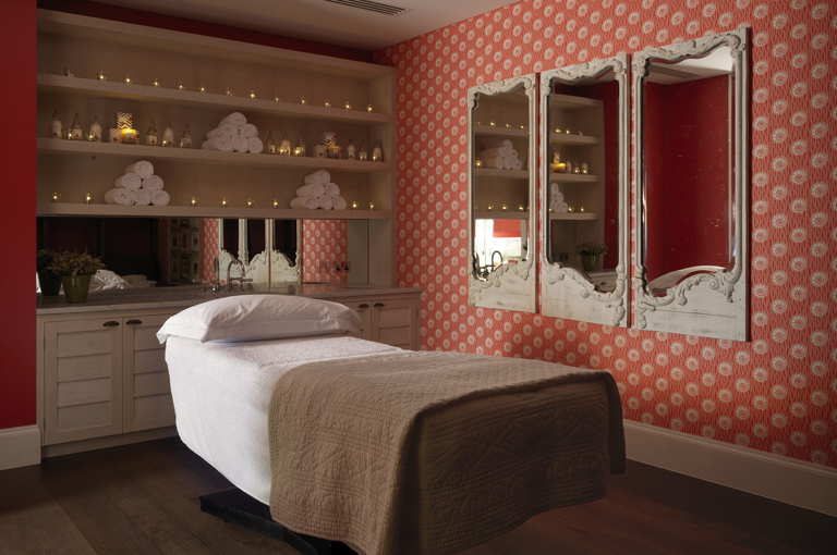 Diagonal shot of a single treatment room, featuring a massage table with fresh white towels, in the Soholistic Spa at Ham Yard Hotel