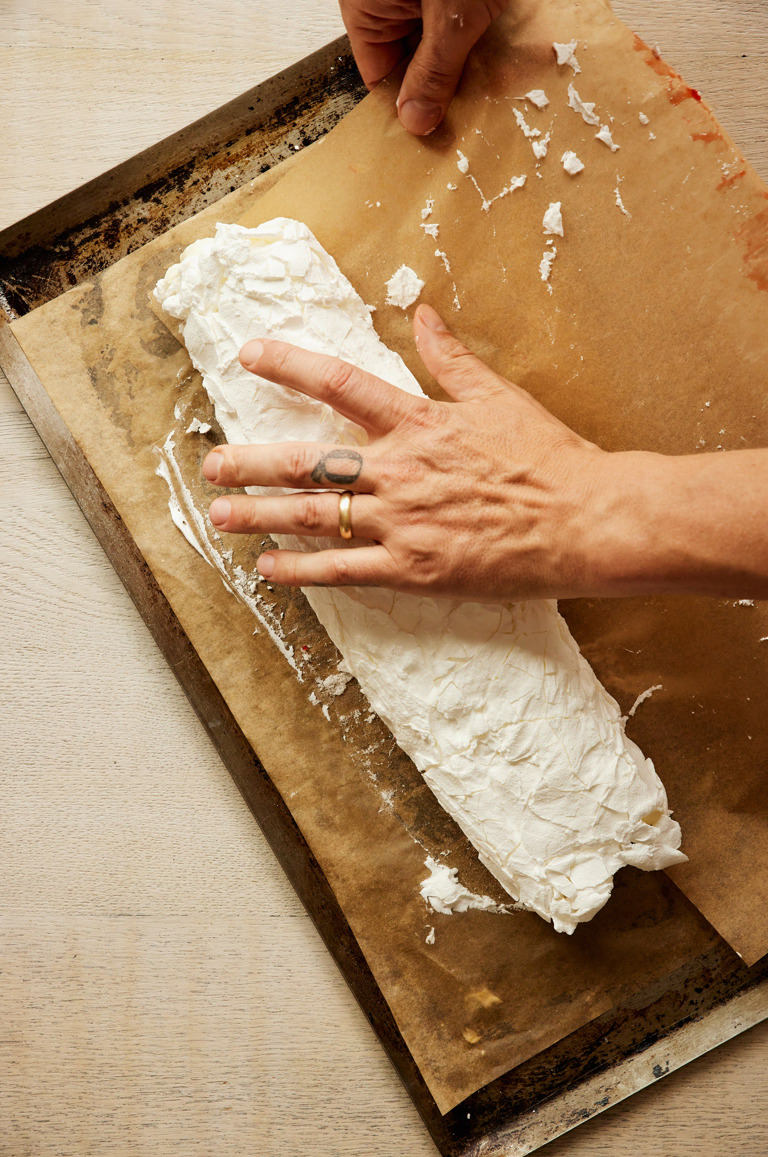 A close-up portrait shot of the process of the strawberry and lime meringue roulade being rolled
