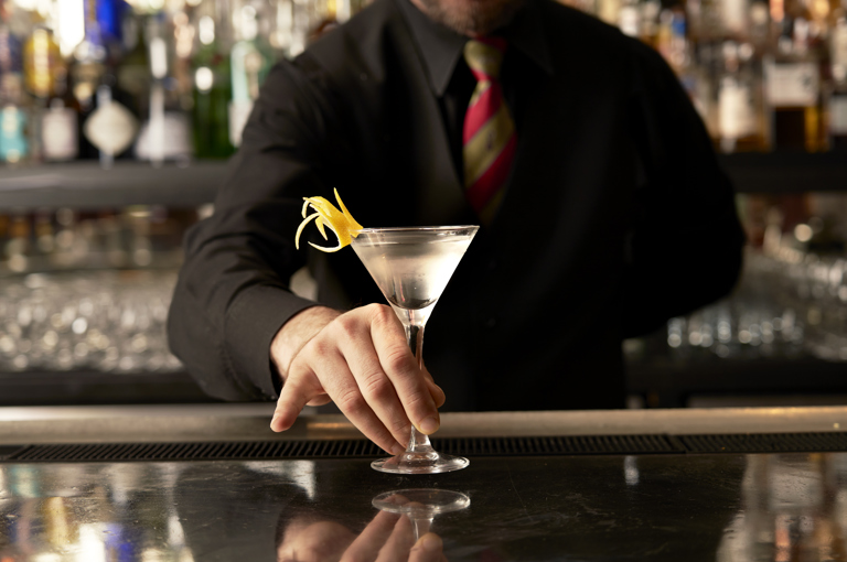 Close shot of a bartender presenting a Martini cocktail on the bar at Brumus