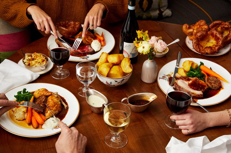 Sunday roast at Refuel. A table with plates of roast chicken, beef and pork surrounded by side dishes