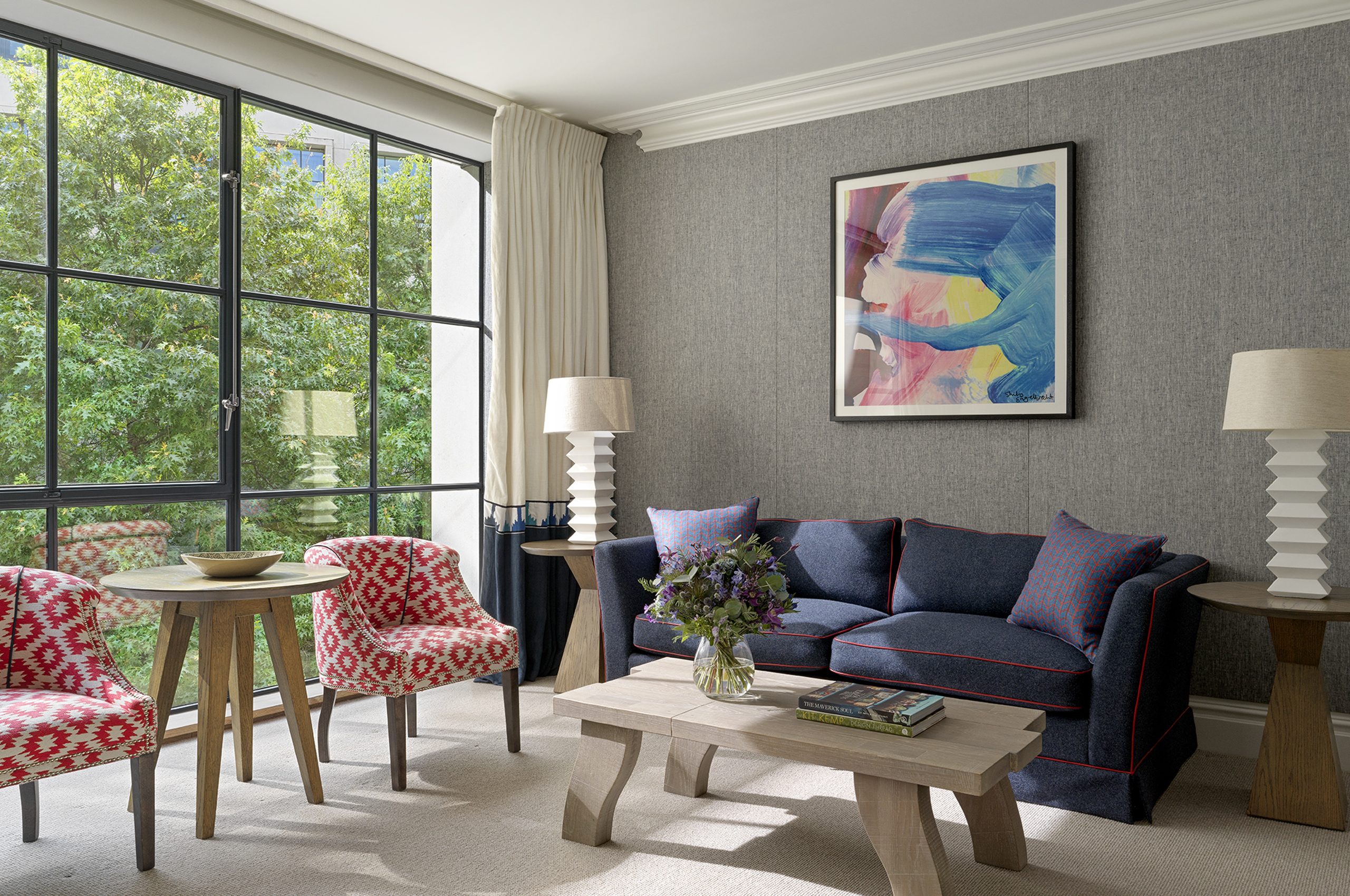 Modern hotel suite with sofa, seating area, and large windows
