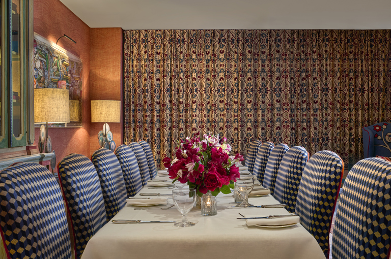 A wide angle shot of the drawing room at Warren Street Hotel set up for private dining: the table is set for twelve, and the curtains have been drawn across the windows