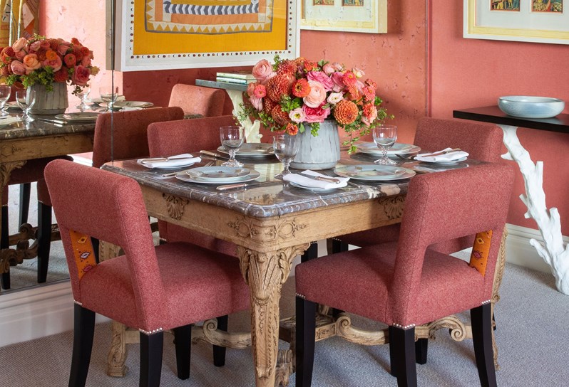 A marble dining table set against a mirrored wall with beaded pendant lights hanging overhead