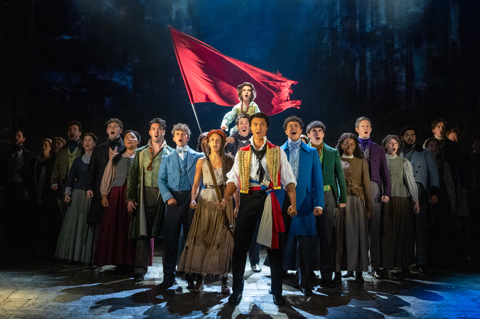 The ensemble cast of Les Miserable singing on stage