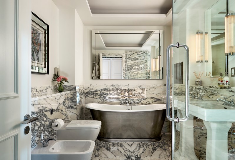 Classic Firmdale granite bathroom with a bath, a bidet, a toilet and 2 sinks with Kit Kemp Rik Rak Shop soap and hand cream.