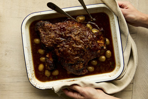 A slow-cooked lamb joint in an oven dish shot from above