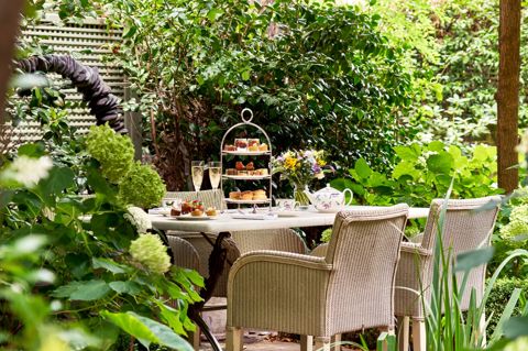 A wide shot of the garden at Number Sixteen: the table is set up for afternoon tea