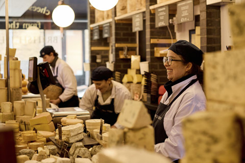 Wide shot of a selection of cheeses with staff at Neal's Yard Dairy